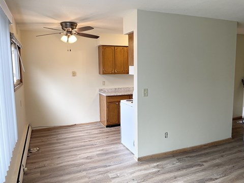 A room with a ceiling fan and wooden cabinets.